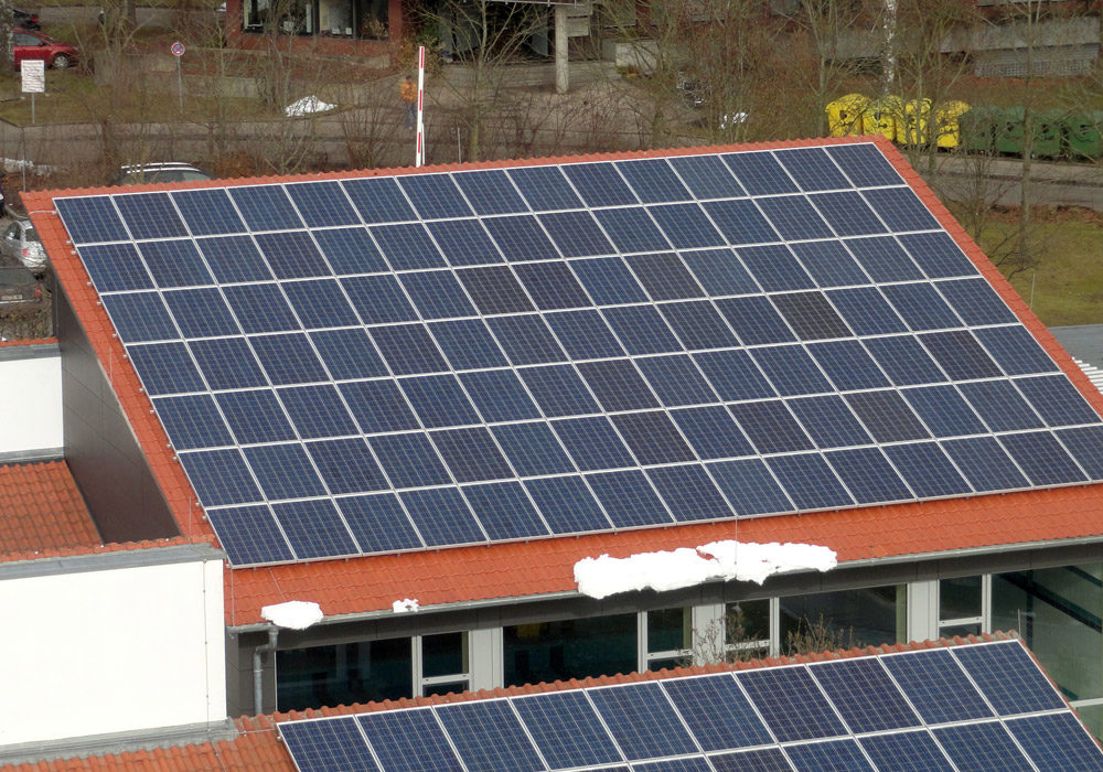 Ziegeldach einer Halle, verdeckt durch eine Solaranlage.